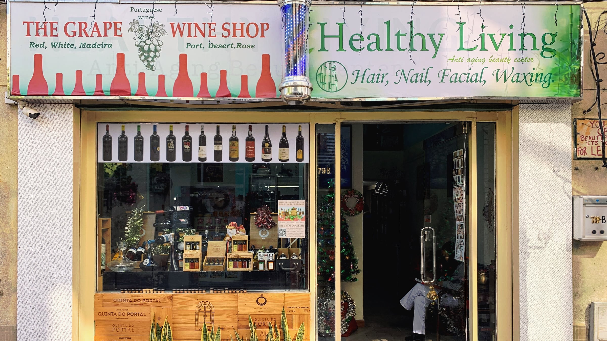 The shopfront of No. 79-B: wine bottles in the window under the signs of The Grape Wine Shop and Healthy Living.